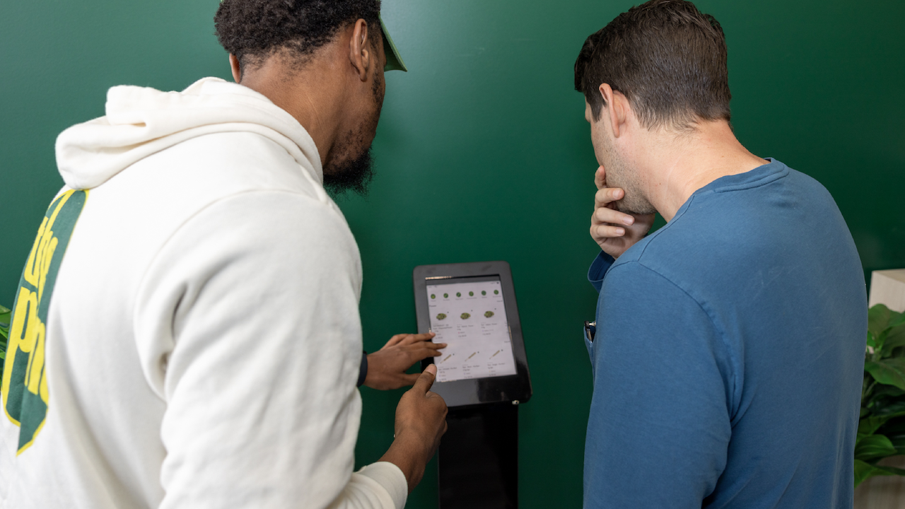 Two men ordering cannabis from the dispensary kiosk.