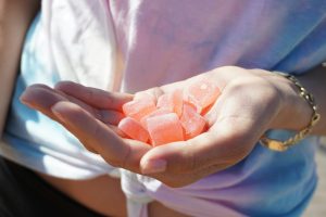 Hand holding a handful of pink THC-infused gummies